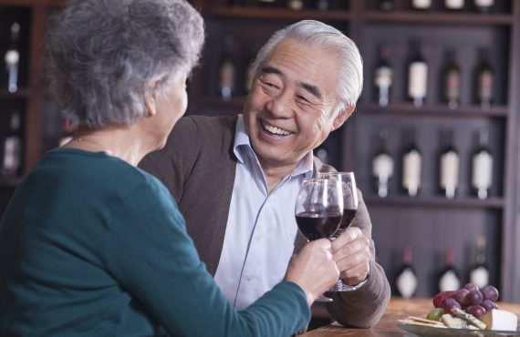 A senior couple toasting and enjoying themselves with glasses of wine, thanks to the support of Senior Healthcare Advisors and their Medicare Advantage plans.